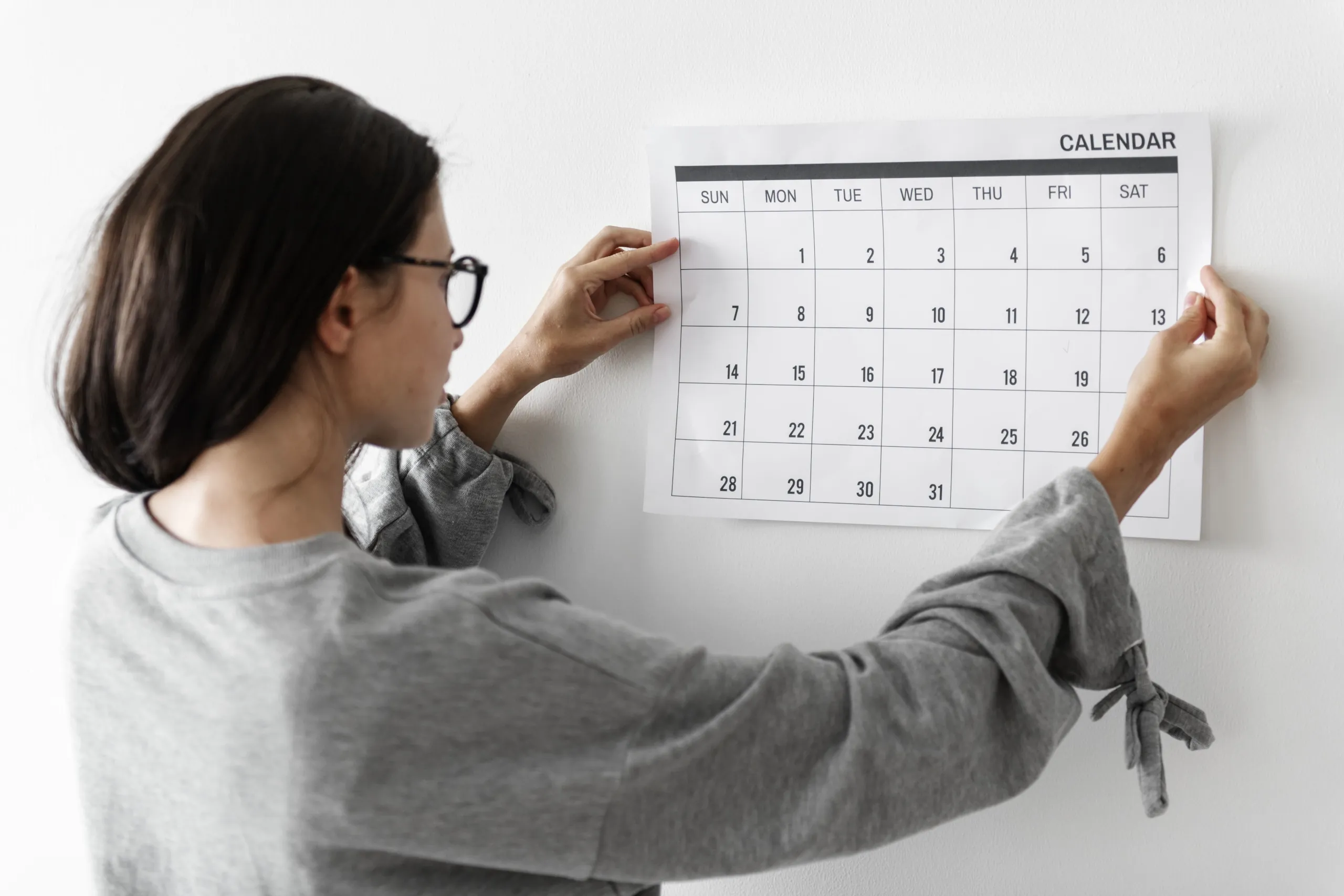 Woman putting calendar on the wall.